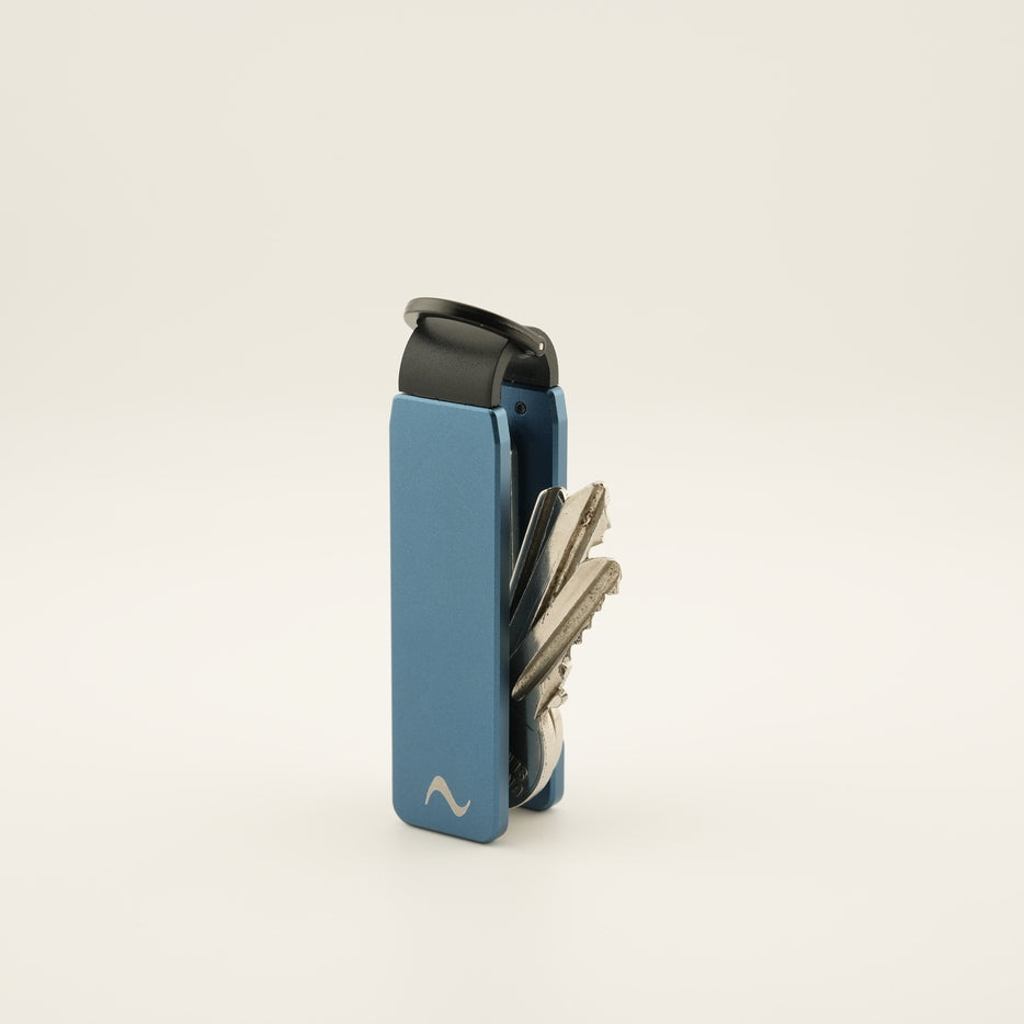 Blue key holder with keys on a light beige background