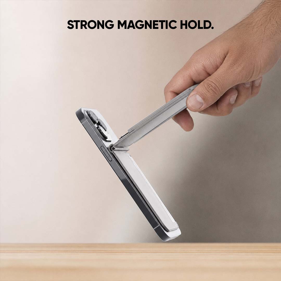 A hand holds a gray magnetic wallet at an angle to demonstrate its strong magnetic hold, with the text 'STRONG MAGNETIC HOLD.' at the top against a neutral beige background.